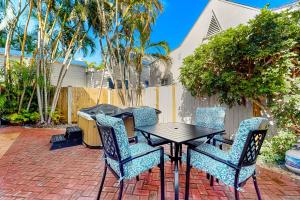a patio with a table and chairs and palm trees at Southernmost Retreat in Key West