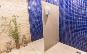 a blue tiled bathroom with a shower with a plant at Flat Hotel Vision Hplus frente para Esplanada - SEM CAFÉ - Acomodação Particular in Brasilia +15 photos
