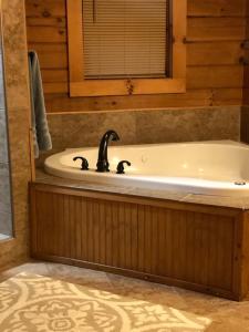 La salle de bains est pourvue d'une baignoire avec un robinet noir. dans l'établissement Swiftwater - Secluded Log Cabin, 