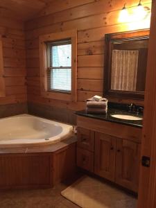 La salle de bains est pourvue d'une baignoire, d'un lavabo et d'un miroir. dans l'établissement Swiftwater - Secluded Log Cabin, 