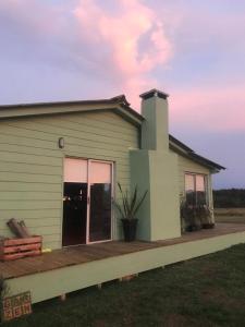 una pequeña casa verde con porche en Chacra marítima en Garzon Jose ignacio, en José Ignacio