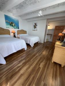 a bedroom with two beds and a wooden floor at Key Colony Beach Motel in Marathon