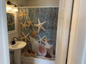 a bathroom with a shower curtain with a sink and starfish at Key Colony Beach Motel in Marathon