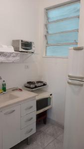 cocina blanca con nevera y microondas en Apartamento Liberdade, en São Paulo