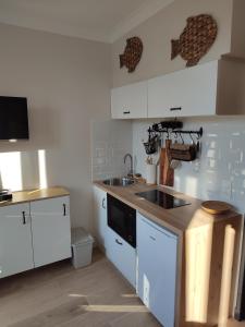 una cocina con armarios blancos y fregadero en un nid d ' Amour, en Cabourg
