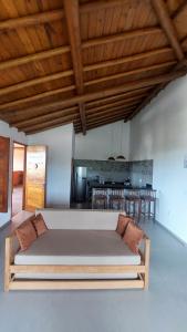 a large couch in a living room with a kitchen at Aldeia Biribiri - Pousada in Caraíva