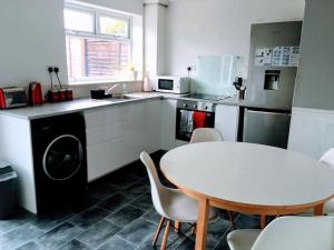 cocina con mesa blanca, mesa y sillas en Aspen House en Birmingham