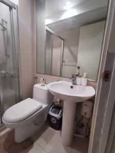 a bathroom with a sink and a toilet and a mirror at Elite Pod 807 Knightsbridge Makati in Manila