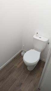 ein weißes WC im Bad mit Holzboden in der Unterkunft Chambre dans appartement près du Roazhon Park in Rennes