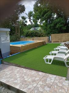 a lawn with chairs and a swimming pool at LESTEPHANIA in Le Moule