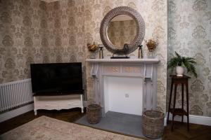a living room with a tv and a mirror at Stable Cottage in Ashbourne