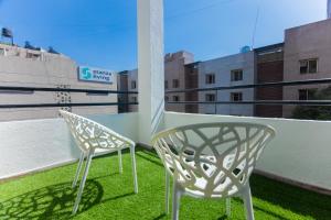 Duas cadeiras brancas sentadas numa varanda com relva verde em La vaccanza Suite -403 em Pune