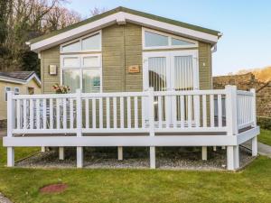 a tiny house with a white fence and a bench at The Hideaway - Heritage Park in Narberth +15 photos
