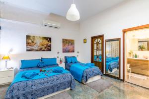 a bedroom with two blue beds and a bathroom at Museo Filangieri Apartment-Suite in Naples