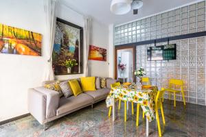 a living room with a couch and a table with yellow chairs at Museo Filangieri Apartment-Suite in Naples