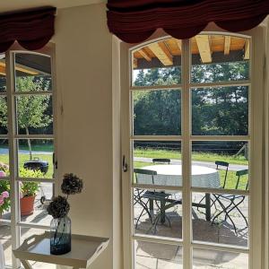 Zimmer mit 2 Fenstern, einem Tisch und einer Terrasse in der Unterkunft Gutshof Ferienwohnung in Seenähe in Dießen am Ammersee