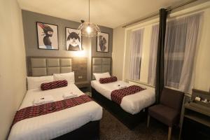 um quarto de hotel com duas camas e uma cadeira em Comfotel GRN em Londres