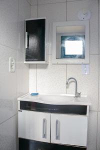 uma cozinha branca com um lavatório e uma janela em Pousada Casa da Penha em Abraão