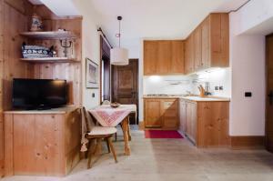 een keuken met houten kasten en een tafel en een televisie bij Sweet Cristallo in Cortina dʼAmpezzo
