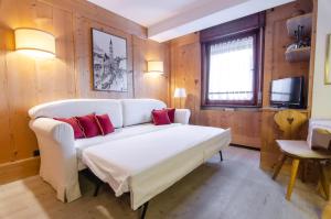 een woonkamer met een witte bank en rode kussens bij Sweet Cristallo in Cortina dʼAmpezzo