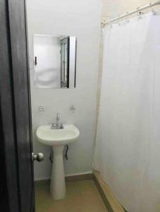 W białej łazience znajduje się umywalka i lustro. w obiekcie Loft Hermoso en Guadalupe w mieście Monterrey