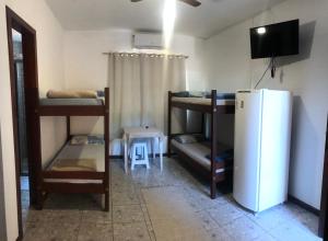 a room with three bunk beds and a refrigerator at Pousada Maria Eduarda in Guarda do Embaú