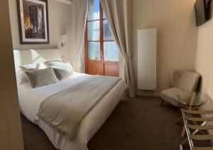 a bedroom with a bed and a window and a chair at Logis Hôtel des Messageries in Arbois