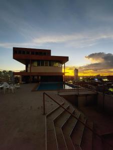a building with a swimming pool in front of a sunset at Taj Mahal Hotel in Manaus