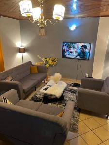 a living room with couches and a flat screen tv at AU COEUR DE BONAMOUSSADI-WIFI-PARKING-GARDIENS-24H in Douala