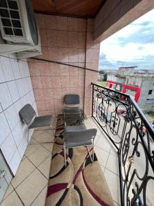 balcone con 2 sedie, tavolo e forno a microonde di AU COEUR DE BONAMOUSSADI-WIFI-PARKING-GARDIENS-24H a Douala