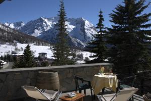 einen Tisch und Stühle auf einem Balkon mit Bergblick in der Unterkunft Hotel Sud Ovest in Sestriere