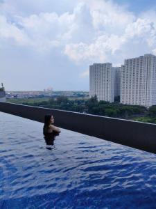 une femme est debout dans un bassin d'eau dans l'établissement Amore Apartment, à Kalisari