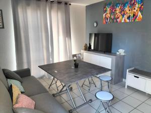 a living room with a table and a couch at T2 avec piscine-Le family 67 in Pierrefiche