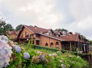 a house with a garden in front of it at Pousada Suiça Mineira Centro in Monte Verde