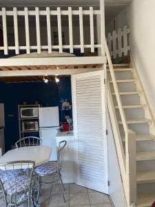 un lit en mezzanine dans une cuisine avec une table et des chaises dans l'établissement Joli appartement mezzanine avec parking et wifi La Roquille, au Cap d'Agde