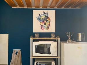 un four micro-ondes sur une table avec un crâne sur le mur dans l'établissement Joli appartement mezzanine avec parking et wifi La Roquille, au Cap d'Agde