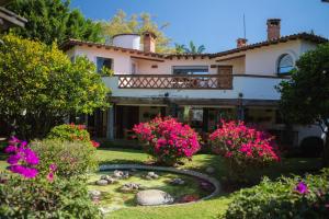 una casa con un jardín con flores rosas y un estanque en Casa Bugambilia, Un Pequeño Hotel en Tepoztlán, en Tepoztlán