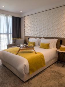 New Hotel Piscine Wellness & Spa في الدار البيضاء: غرفة نوم بسرير كبير مع بطانية صفراء