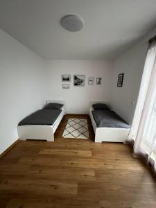two beds in a room with a wooden floor at ApartHotel Roxheim in Roxheim