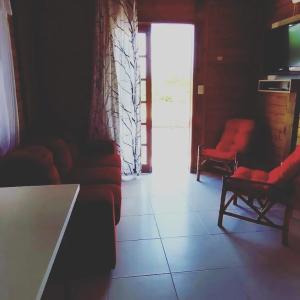 una sala de espera con sillas rojas y una puerta en Chalés Rota do Sol Praia do Rosa, en Praia do Rosa