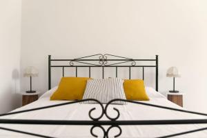 a bed with a black frame and yellow pillows at Trulli Cibelis in Noci