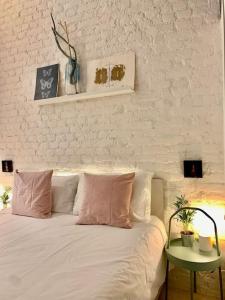 a white bed with pink and white pillows and a table at Stylish flat in Porta Romana-Fondazione Prada in Milan