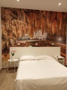 a bedroom with a white bed and a stone wall at Hotel Porta Rivera in LʼAquila