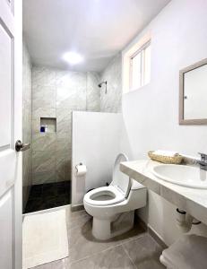 a white bathroom with a toilet and a sink at Residencial Gran Palma in Acapulco