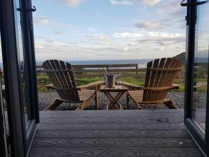 two chairs and a table on a porch with a view of the ocean at Dunbeath Coastal Retreat in Dunbeath