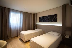 a hotel room with two beds and a window at Zahara Hotel in Limeira