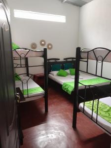 a room with two bunk beds with green sheets at LUNA del DESIERTO TATACOA in Villavieja