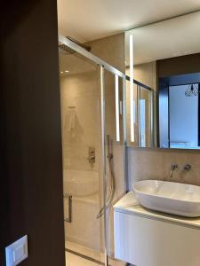 La salle de bains est pourvue d'un lavabo blanc et d'une douche. dans l'établissement Riva 22, à Lugano