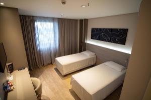 a hotel room with two beds and a desk at Zahara Hotel in Limeira
