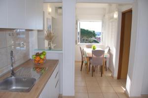 a kitchen with a sink and a table with a window at Apartments Summer Joy in Novalja